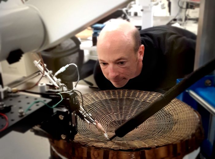 Asher leaning over a basket being examined in the laboratory