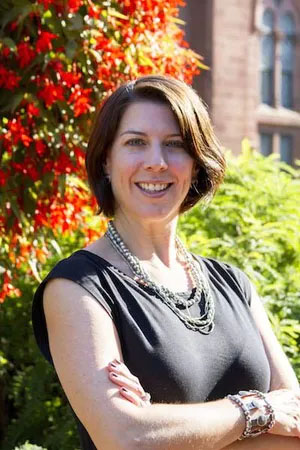 Head shot of Aviva Rosenthal standing in garden with arms folded