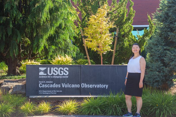 Kadie Bennis poses next to USGS Cascades Volcano Observatory sign