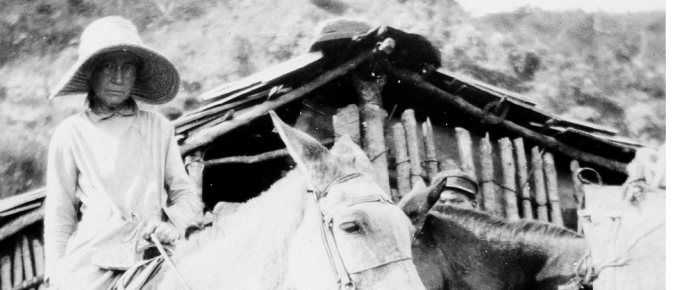 In this picture, Chase is on horseback in front of a wood hut.