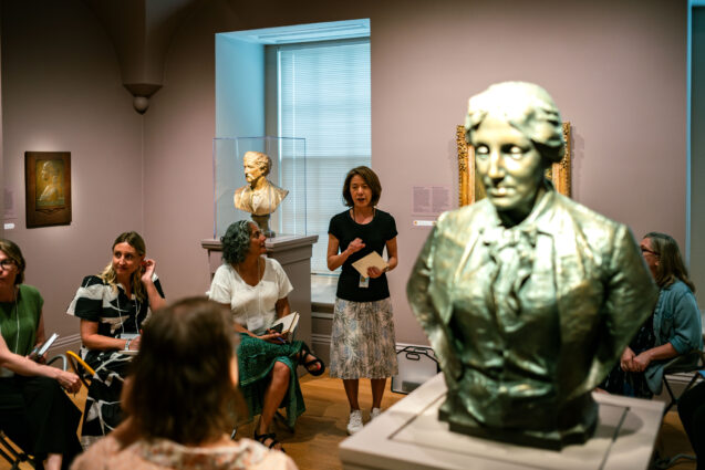 Educator speaking to class about sculpture of woman