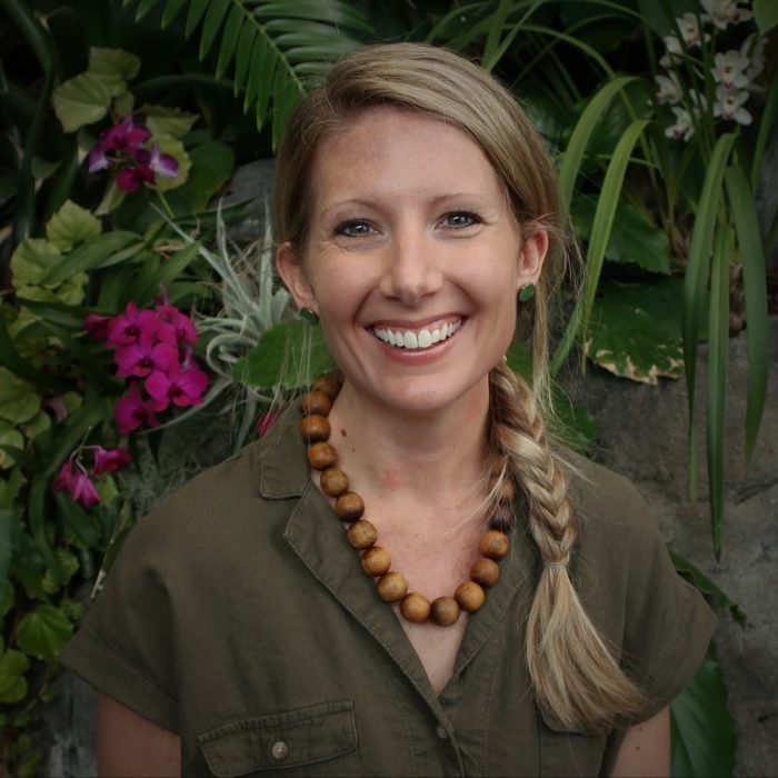 Head shot of Dr Erin Spear against tropical foliage