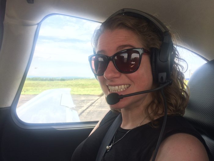 Martin in sunglasses and headphones smiling from passenger side of plane cocklpit