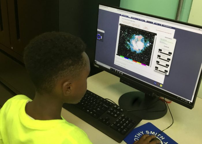 Young boy looking at image of space on computer screen