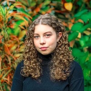 Headshot Emily Driehaus posing against background of foliage