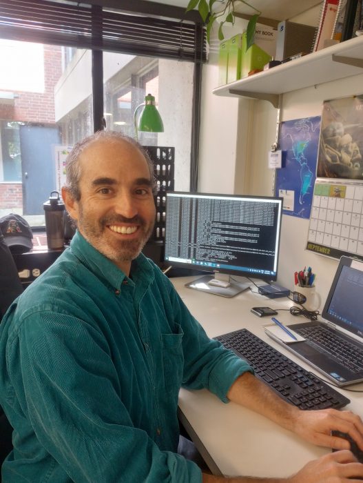 Gonzalo smiles for the camera while working at a computer at his desk