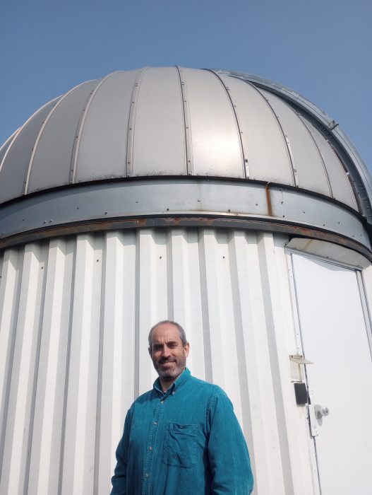 Gonzalo stands in front of telescope dome taking up most of the background