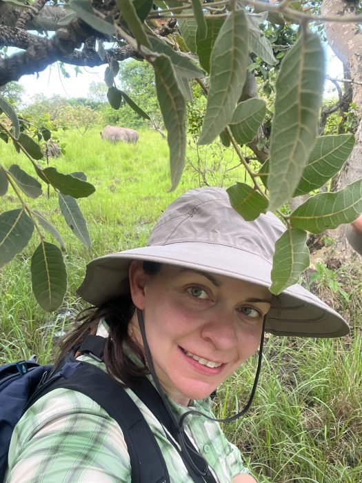 Missy Hawkins close-up selfie in the field with white rhino in the background