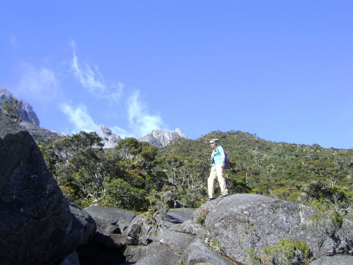 Medium view of Missy Hawkins standing on rock with mountains in the background