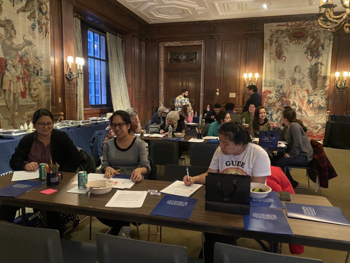 Teachers working and talking at tables in paneled room with tapestries