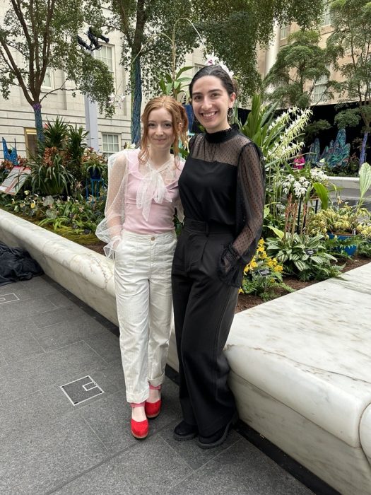 Sophia and Talia pose in Kogod COurtyard among orchids