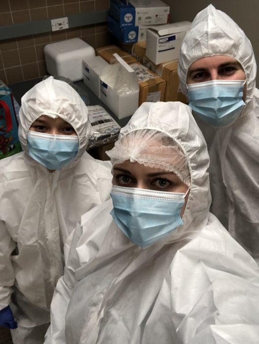 Missy Hawkins and two colleagues wearing protective suits, head coverings and masks