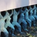 Detail of sculpture installation "Public Figures" showing statues of people holding up plinth