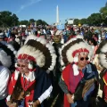 Throngs of Native Americans, many in traditional headgear, on the Mall with the Washington Monument in the background