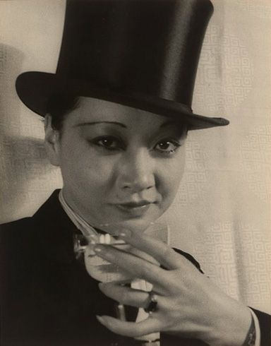 Black and white photo of Anna May Wong in top hat drinking champagne