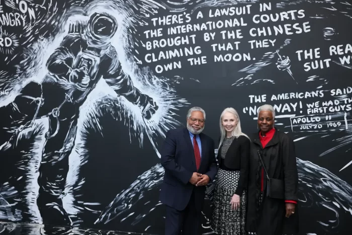 Secretary Bunch, Melissa Chiu and Maria Marable-Bunch in front of art installation drawing of astronaut wit text