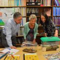 Three people stand over a table filled with scientific speciments