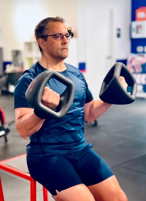 Photo of Jim Di Loreto in workout gear doing curls in the gym