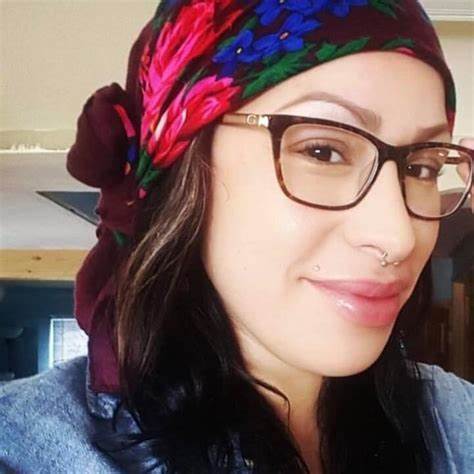 Close-up portrait of Santiago wearing glasses and colorful headscarf