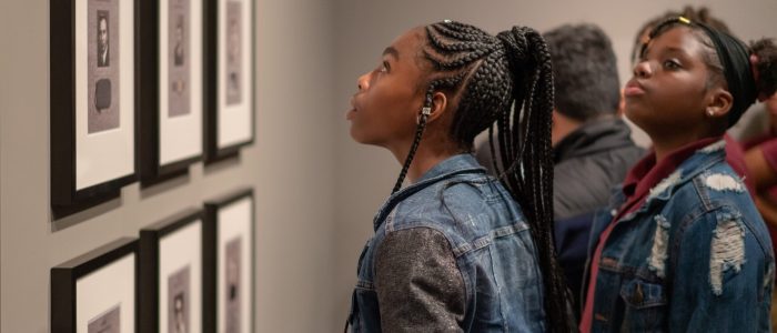 Young African American woman with braids gazes at a mounted artwork at NMAA