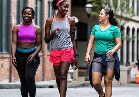 Three women in workout gear walking together and chatting