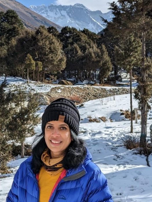 Mani Lanka poses on snow-covered trail with mountains in the background