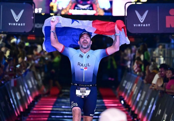 Raul de Leon crosses the finish line of an Ironman triathalon while carrying the Panamanian flag