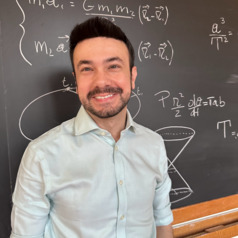 Fabio Pacucci stands in front of a blackboard covered with equations