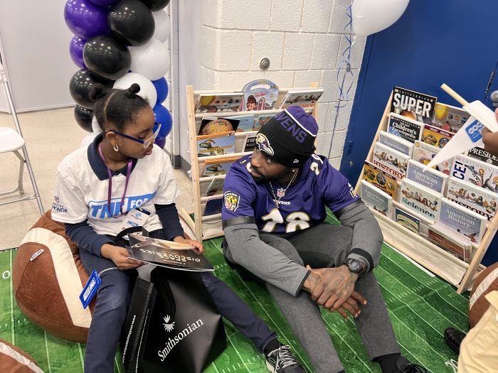 West listens as a young girl beside him reads from a book
