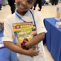 A young girl cradles several books, including "Paloma's Songs for Puerto Rico"