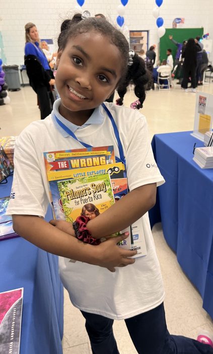 A young girl cradles several books