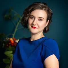 Head shot of Bethanee Bemis wearing dark blue dress photographed against black background