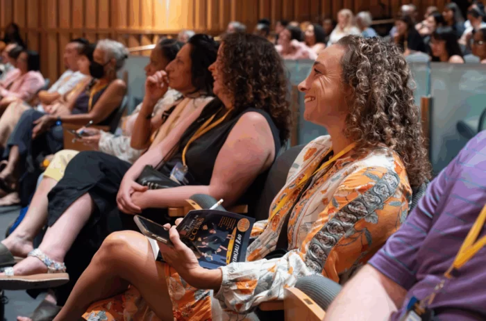 People in audience smiling as they listen to a presentation